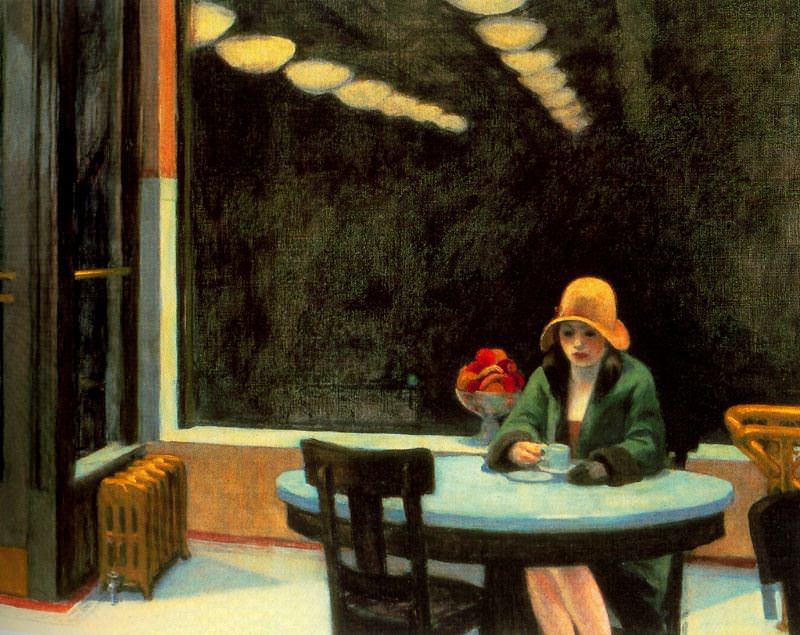 Woman seated at a table by herself in a mostly restaurant.