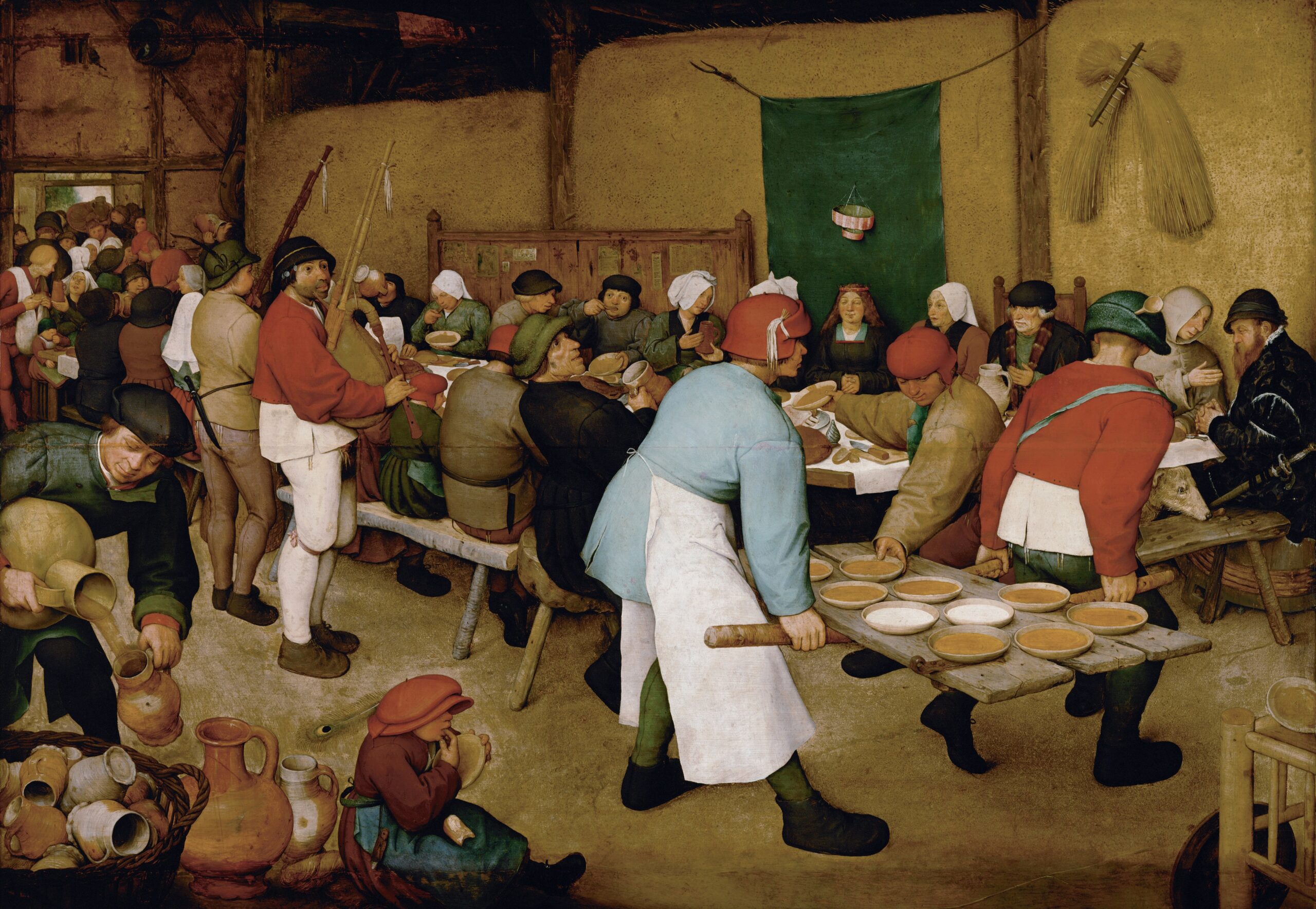 Many people seated at long tables while sharing and being served food.