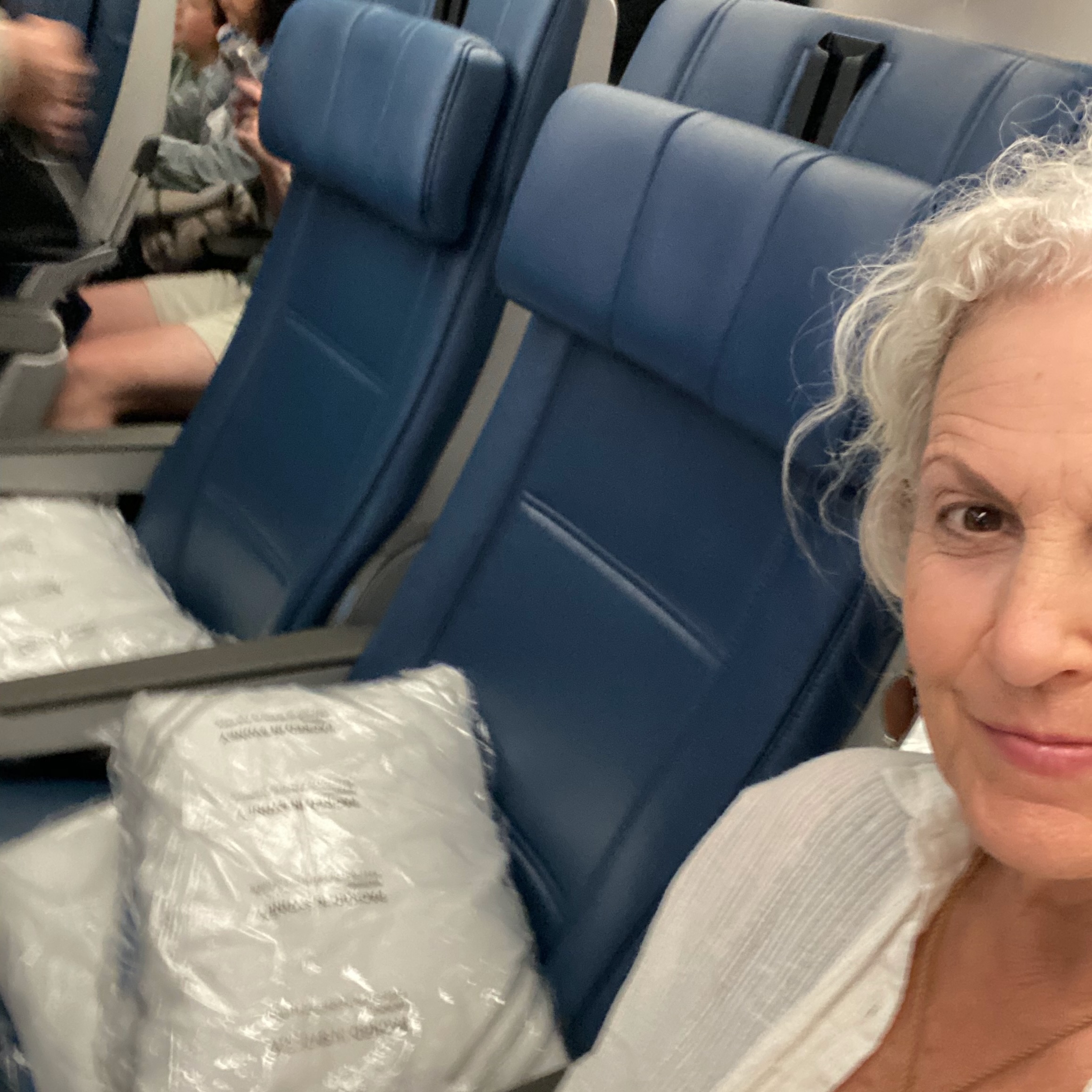 A photo of the author in an airplane seat, the two next to her empty. 