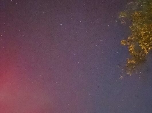 The night sky with stars and the pink glow of the Northern Lights